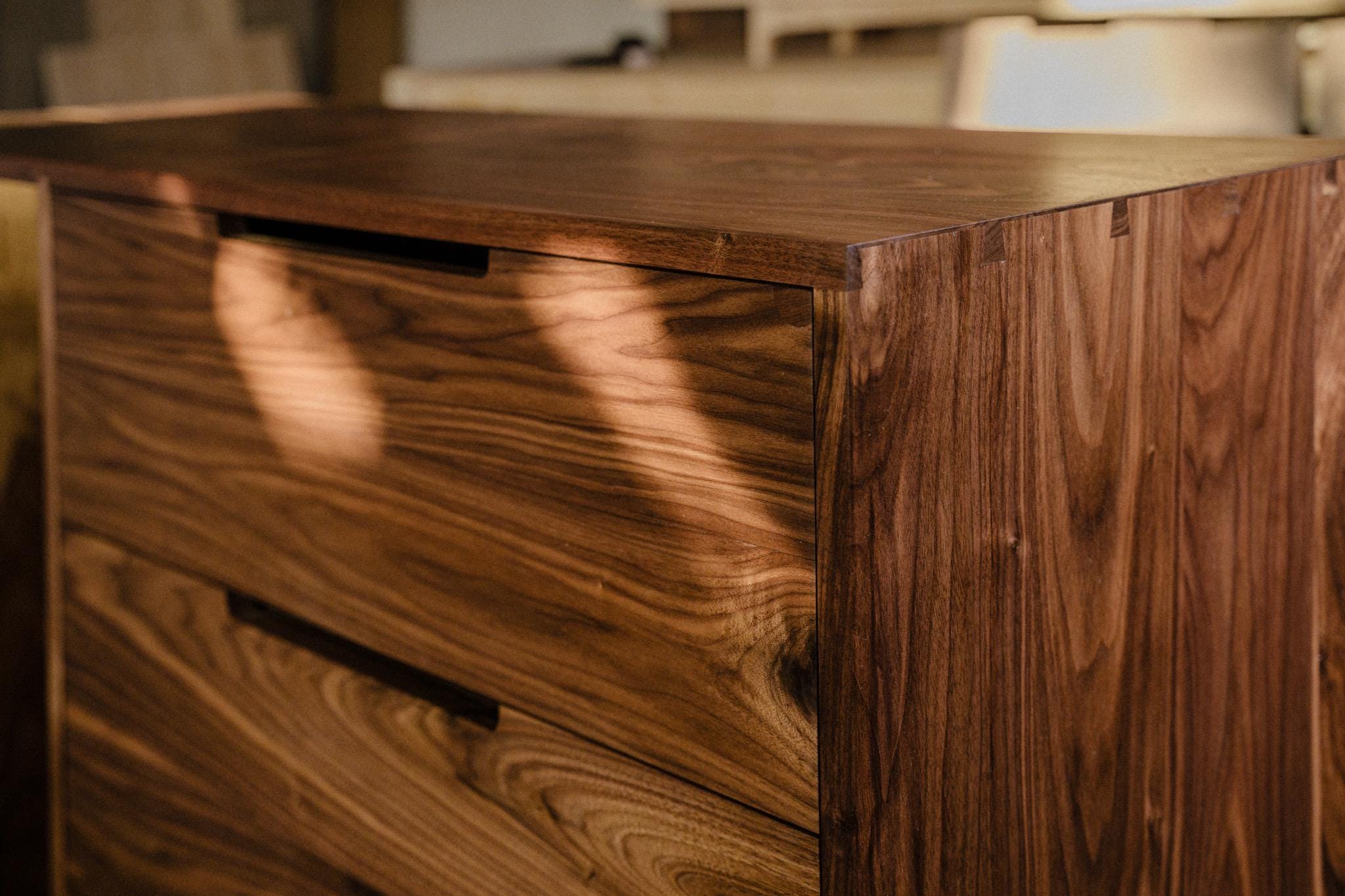 Close up of sunlight shining on the “Santa Elena” custom wooden cabinet, representing an example of fine furniture design by Handhold Studio in Eugene. 