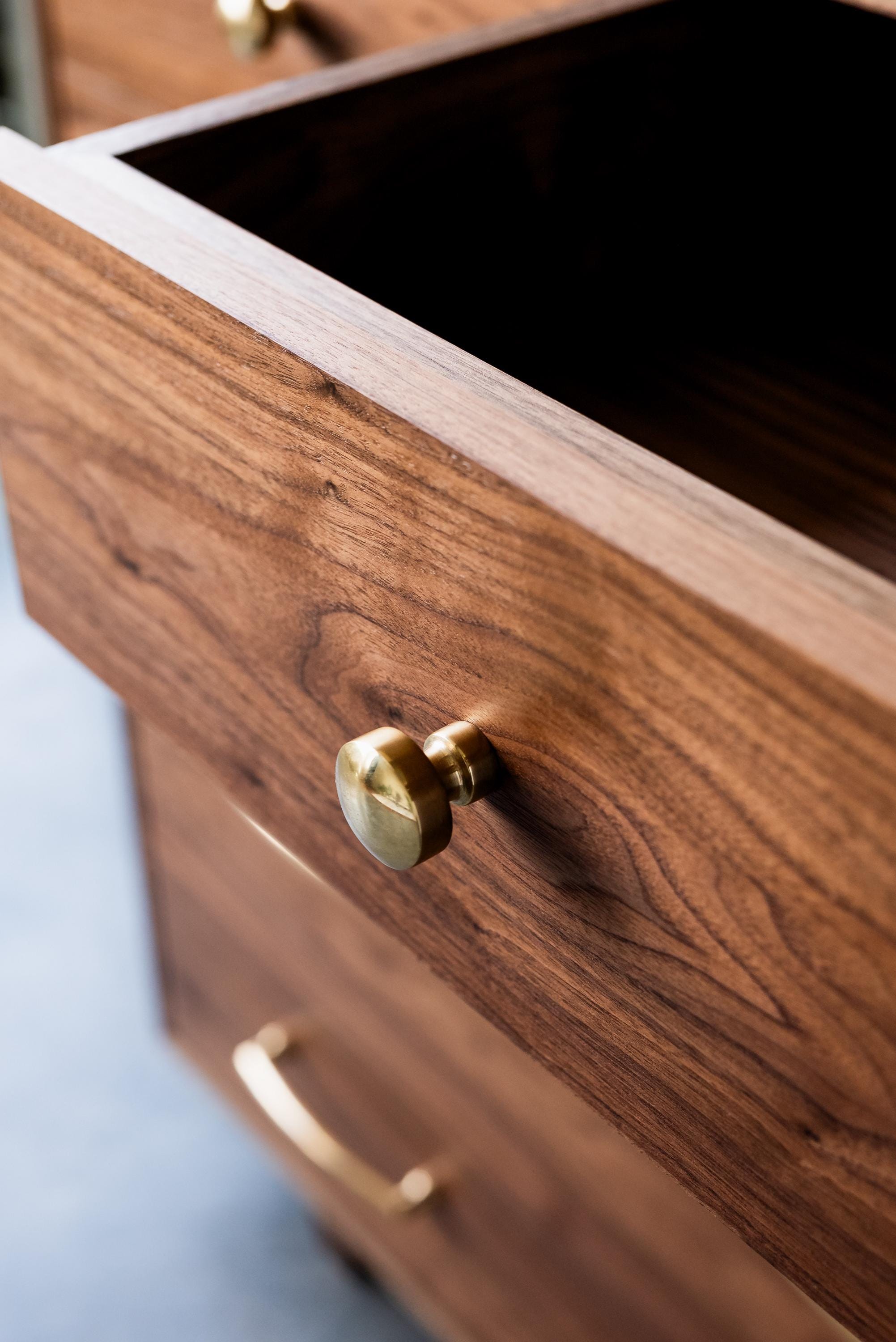Close up of a golden knob on a drawer of a custom wooden dresser created by Handhold Studio, a fine furniture designer in Eugene, Oregon.  
