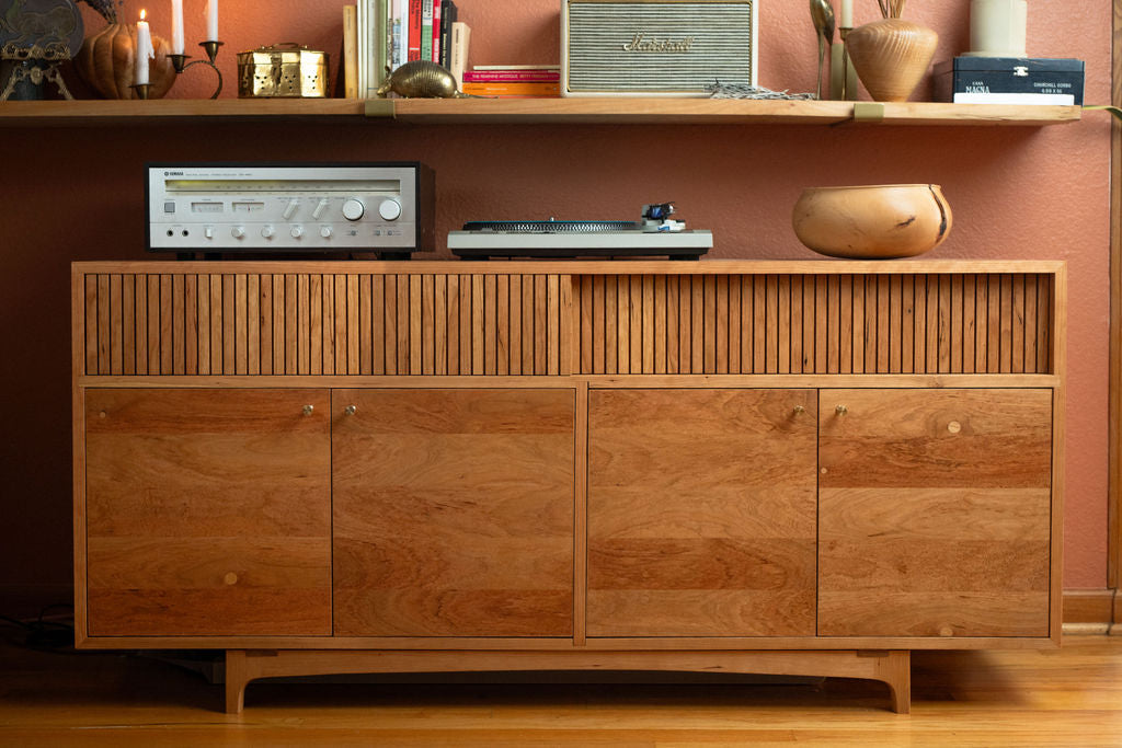 A custom wooden cabinet with a record player and bowl sitting atop it, representing and example of fine furniture design by Handhold Studio in Eugene, Oregon. 