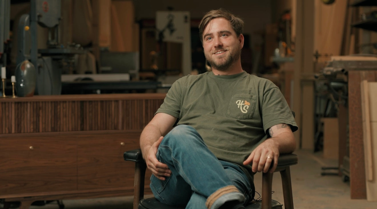 Fine furniture designer, Christopher, of Handhold studio in Eugene, sits in a chair.