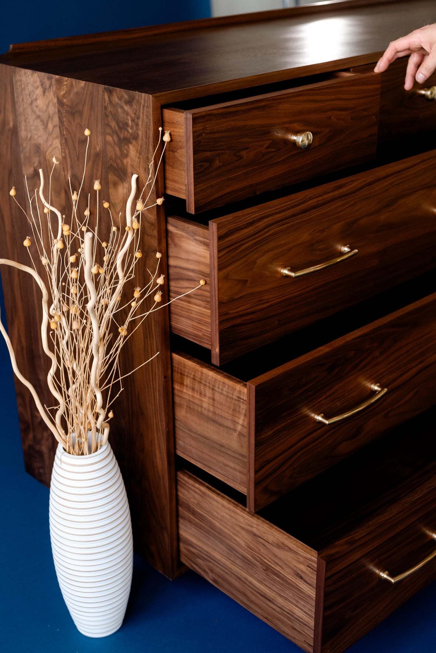 A hand opening the top drawer on The “Levine Dresser," representing an example of custom fine furniture design by Handhold Studio in Eugene, Oregon.  