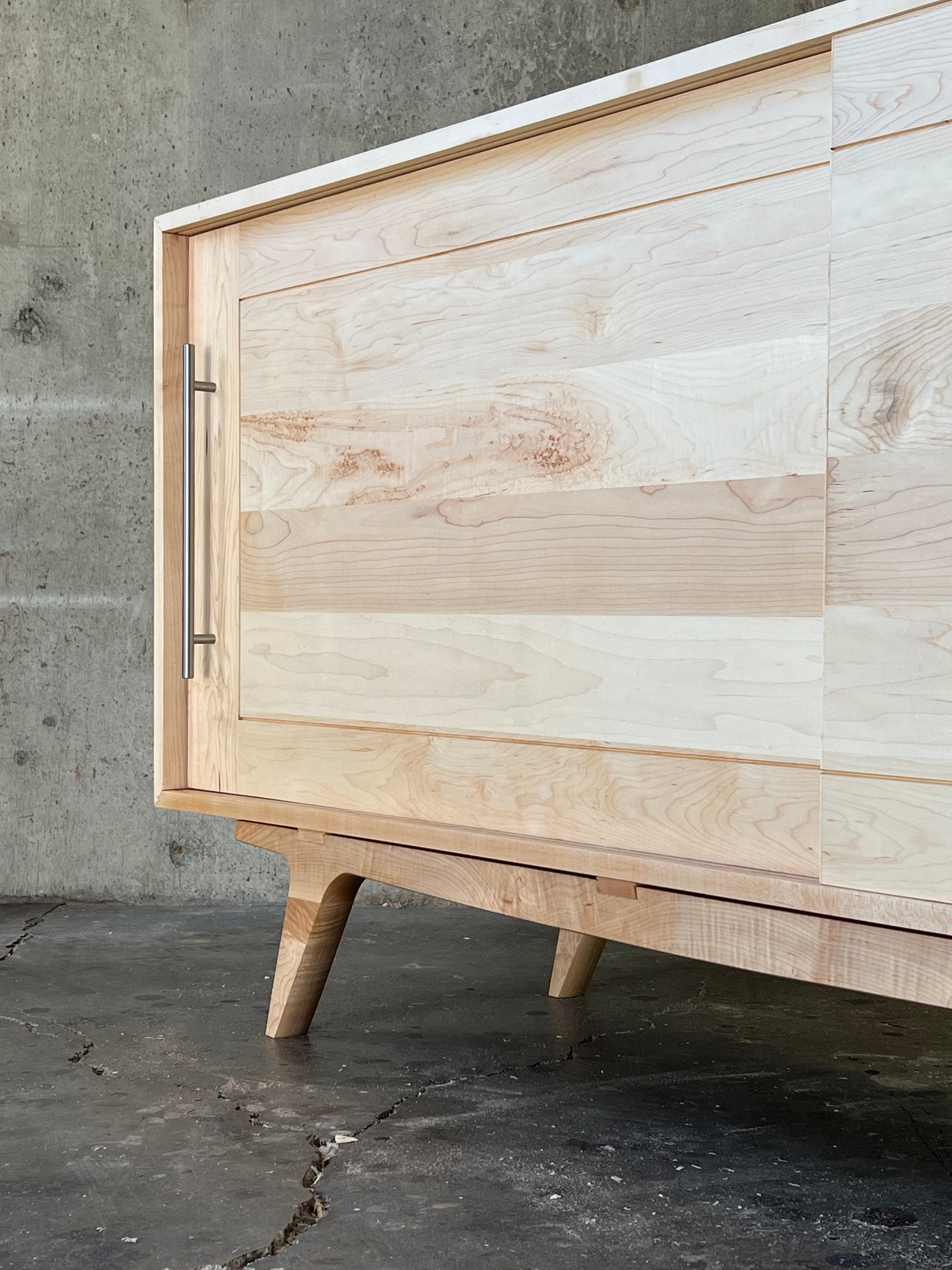 A custom maple wood media cabinet, representing the woodworking design style of Handhold studio.